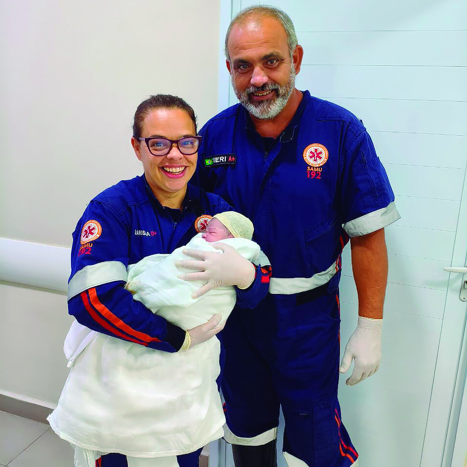 A técnica de enfermagem Larissa carrega Moisés ao lado do condutor Roberto Neri. CRÉDITO: Divulgação|